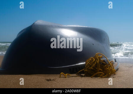 Bateau chaviré sur la plage de sable. Du beau temps et de petites vagues Banque D'Images