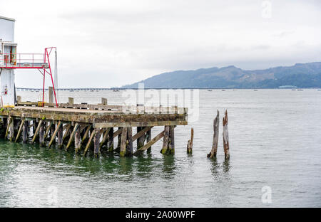 Bâtiments en bois commercial blanc d'un ancien pilote de pêche et de pier avec piles de bois qui dépasse de l'eau à l'échelle de l'embouchure du fleuve Columbia je Banque D'Images