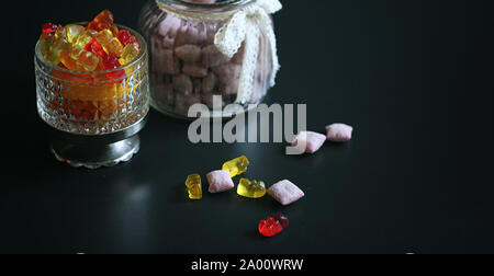 Marmelade dans un vase sur la table. Bonbons dans un bol sur un fond noir. Jelly multicolore des bonbons pour les enfants. Banque D'Images