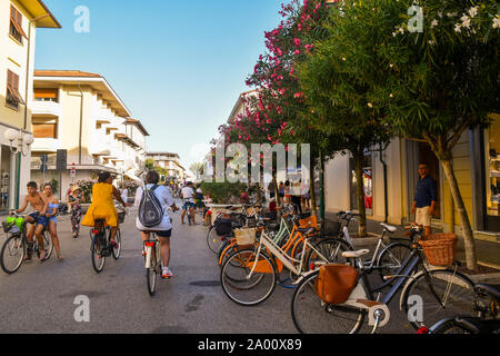 Vue sur la rue de la mer ville de Forte dei Marmi avec des gens sur des vélos, cycles stationnés et la floraison des arbres en été, Oléandre, Lucques et la Versilia, Italie Banque D'Images