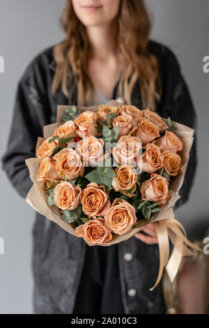 Couleur café cappuccino, fleurs roses à l'eucalyptus. Petit magnifiques bouquets dans femme la main. Boutique de fleurs concept. Livraison de fleurs Banque D'Images