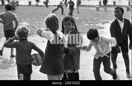 Southall, Londres 1972. Asiatiques, Noirs et Blancs enfants jouant dans la cour de l'école. Après Idi Amin commandé 30 000 Asiatiques hors de l'Ouganda avec préavis de 90 jours, ceux avec un passeport britannique dirigé vers l'Angleterre. Ils ont été forcés de quitter leurs fonds, leurs biens et possessions derrière. Ces images documentent la vie de certaines des personnes lorsqu'ils se sont installés dans la région de Southall, à l'ouest de Londres. Un aperçu de la vie il y a 47 ans pour les immigrés au Royaume-Uni. Photo par Tony Henshaw Banque D'Images