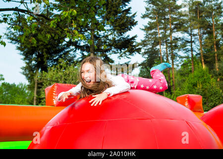 Happy little girl ayant beaucoup de plaisir sur un château gonflable lors d'un saut. Banque D'Images
