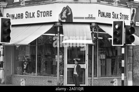 Southall, Londres 1972. Un jeune garçon asiatique en dehors d'un sari de soie et boutique. Après Idi Amin commandé 30 000 Asiatiques hors de l'Ouganda avec préavis de 90 jours, ceux avec un passeport britannique dirigé vers l'Angleterre. Ils ont été forcés de quitter leurs fonds, leurs biens et possessions derrière. Ces images documentent la vie de certaines des personnes lorsqu'ils se sont installés dans la région de Southall, à l'ouest de Londres. Un aperçu de la vie il y a 47 ans pour les immigrés au Royaume-Uni. Photo par Tony Henshaw Banque D'Images