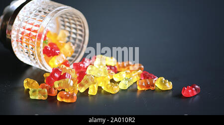 Marmelade dans un vase sur la table. Bonbons dans un bol sur un fond noir. Jelly multicolore des bonbons pour les enfants. Banque D'Images