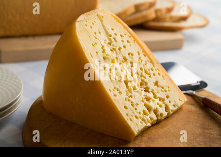 Morceau de fromage néerlandais Stolwijker avec trous sur une planche à découper pour le déjeuner Banque D'Images