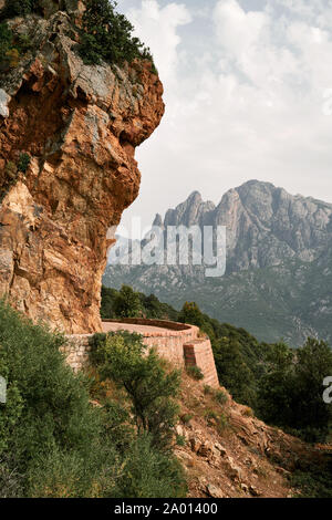 Capo d'Orto mountain et l'étroite route sinueuse à travers la couleur rose granite rock côte du golfe de Porto en Corse France. Banque D'Images