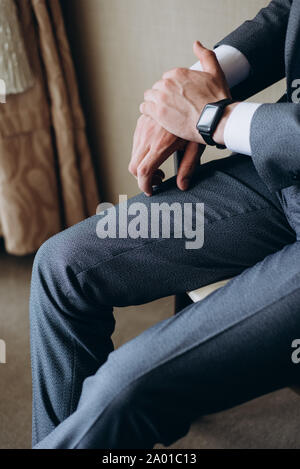 Concepteur de réveil sur la main de l'homme d'affaires. Homme dans un costume gris est assis sur une chaise Banque D'Images