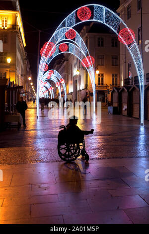 Lisbonne - Silhouette d'un cul-de-jatte mendiant dans un fauteuil roulant sur la Rua Augusta. Banque D'Images