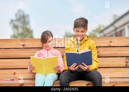 La lecture de livres pour enfants à l'école assis sur un banc Banque D'Images