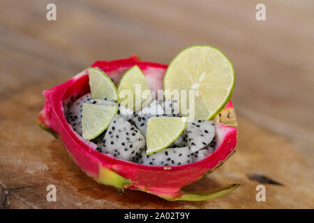 Tranches de fruits du dragon et tranches de citron vert dans une bande de jus de fruit du dragon sur fond de table en bois. Banque D'Images