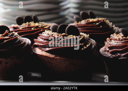 Muffins au chocolat noir garni de glaçage au chocolat, Close up, sucer les plaques dans l'arrière-plan