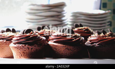 Muffins au chocolat noir garni de glaçage au chocolat, Close up, sucer les plaques dans l'arrière-plan