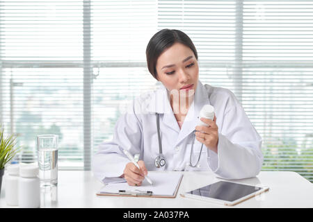 Female doctor holding a box of pills in medical office Banque D'Images