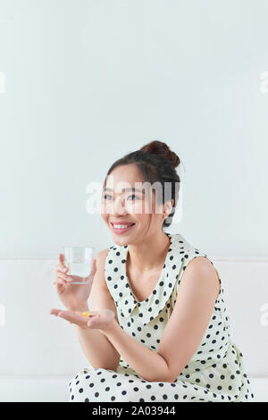 Femme avec des pilules et verre d'eau à l'intérieur Banque D'Images