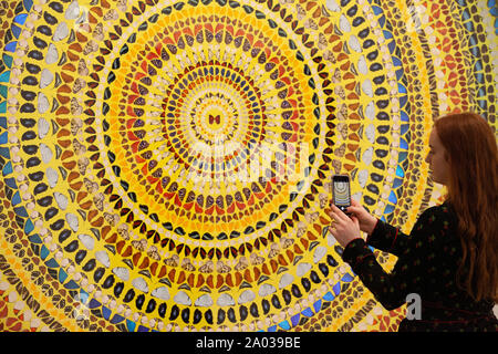 Étudier l'un des membres du personnel de la galerie Damien Hirst's images de sa série 'Mandalas', juste avant qu'il s'ouvrir à White Cube Mason's Yard Gallery de Londres. Les images sont faites à partir d'un collage d'ailes de papillon. Banque D'Images