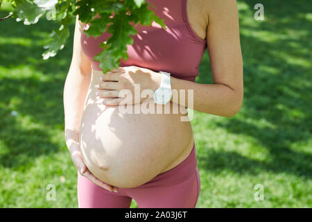 Close-up of young pregnant woman in pink clothing profiter de la nature de l'été et de sa grossesse Banque D'Images