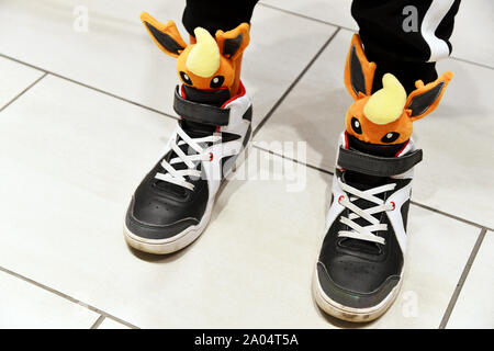Baskets montantes noires et blanches associées à des chaussettes fantaisistes avec mascottes Pokémon présentant des visages en peluche 3D de Flareon dépassant des ourlets - Tokyo - Japon Banque D'Images