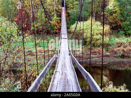 La suspension fait main en bois ancien pont suspendu sur la rivière sur un parc naturel automne fond. Soft focus sélectif. Copie du texte de l'espace. Pont automne chute Banque D'Images