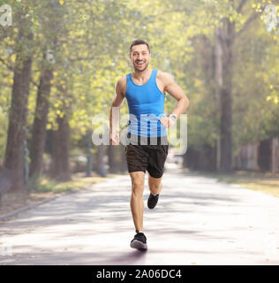 Portrait d'un jeune mec du jogging dans un parc et souriant Banque D'Images