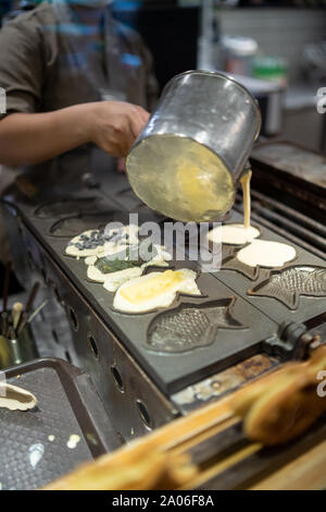 Kaohsiung, Taiwan : taïwanais traditionnel japonais / gaufres. Image employés asiatiques femmes Verser la pâte dans un fer à repasser chaud cast à faire en forme de poisson Banque D'Images