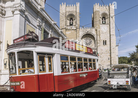 Lisbonne, Portugal - août 2019 : tramway touristique et les tuk tuk en passant en face de la cathédrale par la rue pavée Banque D'Images