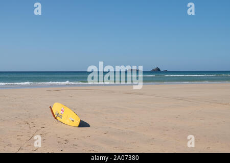 La planche de surf jaune RNLI a été soutenue et a pointé vers la mer sur Constantine Beach, North Cornwall, Angleterre, Royaume-Uni Banque D'Images