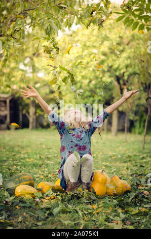 Heureux belle enfant, à lancer des feuilles dans le jardin d'automne Banque D'Images