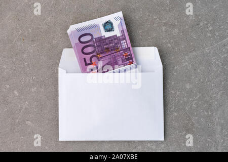 Avec une enveloppe blanche 500 euro bills. Pile de cinq cent billets d'euros à ouvrir le courrier enveloppe sur béton. Billets pliés dans une enveloppe comme un présent Banque D'Images