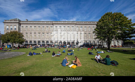 Students relaxing et ejoying une journée tranquille avec un temps magnifique sur la pelouse à l'extérieur du Livre de Kells, Ancienne Bibliothèque Trinity à Dublin, Irlande. Banque D'Images