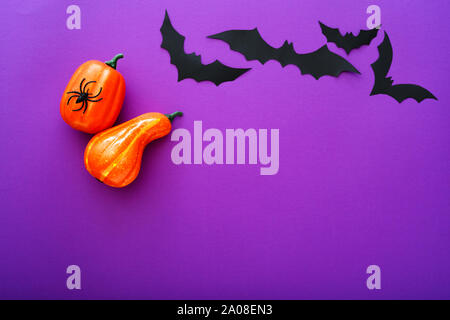 Fond d'Halloween avec des citrouilles, araignées et chauves-souris papier noir sur fond violet, vol . Copier l'espace. Décoration Halloween et le concept. Banque D'Images