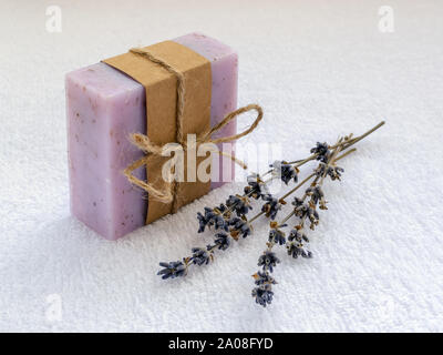 Avec un savon violet aromatiques sèches fleurs de lavande. Savon fait à la main sur une serviette en coton blanche. Produits d'hygiène et de toilette naturels aux herbes Banque D'Images