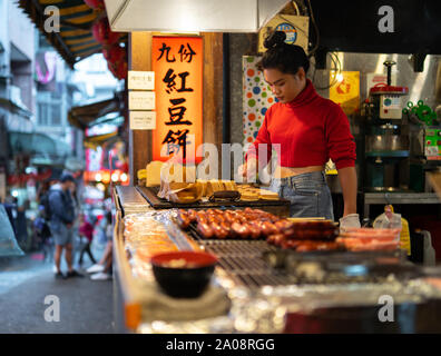 Jeune femme préparant taiwanais / roue (gâteaux japonais) Imagawayaki avec haricot azuki rouge le remplissage à street food shop à jiufen Old street. Banque D'Images