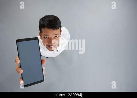 En Smartphone smiling man main ci-dessus Vue de dessus sur fond gris studio Banque D'Images