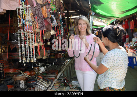 Une femme de race blanche (touristique) parution dans un marché traditionnel en plein air avec une femme birmane traditionnelle près de Bagan au Myanmar du vendeur souriant à la Cam Banque D'Images