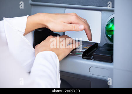Close-up of Woman's Hand saisie de code Pin sur le clavier de la machine ATM Banque D'Images