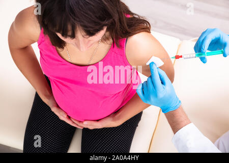 Close-up of Doctor Wearing Blue Gants vaccinant Jeune femme enceinte en clinique Banque D'Images