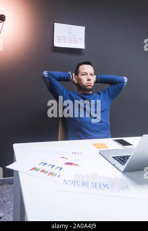 Thoughtful businessman looking away while relaxing in office Banque D'Images