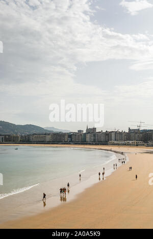 Les gens qui marchent le long de la plage sur un lundi matin à San Sebastian, Espagne. Banque D'Images