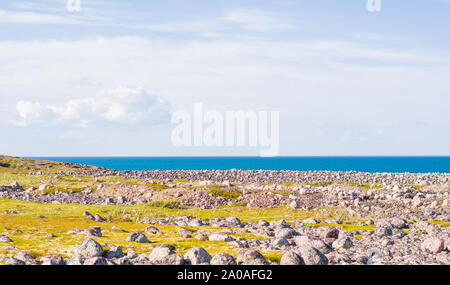 Rocky seashore. D'énormes rochers arrondis sur la plage. La mer de Barents brille avec toutes les nuances de bleu en été. Parmi les pierres peuvent être vus à o Banque D'Images