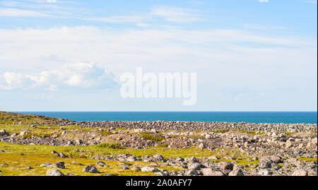 Rocky seashore. D'énormes rochers arrondis sur la plage. La mer de Barents brille avec toutes les nuances de bleu en été. Parmi les pierres peuvent être vus à o Banque D'Images