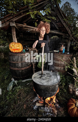 Vieille sorcière potion mortelle de brassage pour l'Halloween dans un pot en fonte Banque D'Images