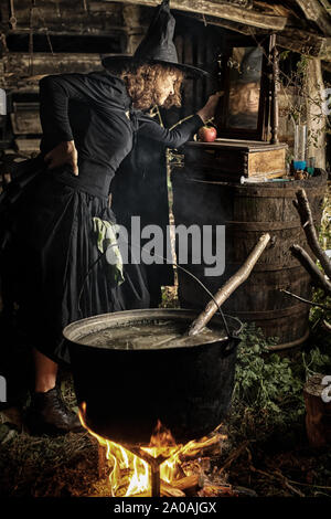 Vieille sorcière potion mortelle de brassage pour l'Halloween dans un pot en fonte Banque D'Images