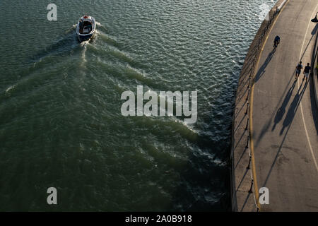 La lumière et les ombres : un petit bateau de pêche revient à le port-canal de la ville de Pescara et certains services et la route sur la rive, au coucher du soleil. Banque D'Images