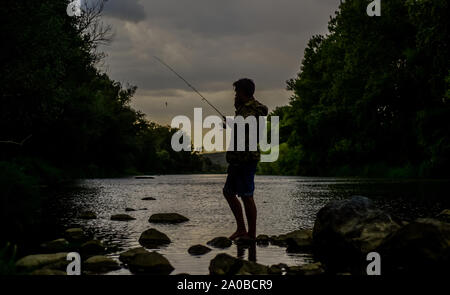 Bonne soirée. fois la pêche. L'activité sportive et de loisirs.. week-end d'été montrent la technique de pêche pêcheur utiliser la baguette. expérimenté fisher attendre que des poissons dans l'eau. man la capture de poissons. mature man fly fishing. Banque D'Images