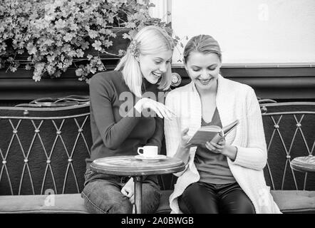 Lecture livre inspirant. L'amélioration d'individu et de l'éducation. Discuter de librairie populaire. Réserver chaque fille devrait lire. Girls friends sitting café terrasse boire du café. La littérature féminine. Banque D'Images