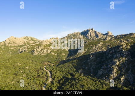 Vue de dessus, superbe vue aérienne de certaines montagnes de granit avec une route qui les traverse. Sardaigne, Italie. Banque D'Images