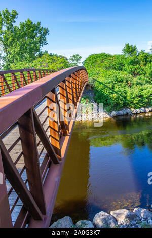 Une passerelle avec garde-corps en métal couleur rouille traverse sur un ruisseau, la connexion de deux côtés d'une allée. Banque D'Images