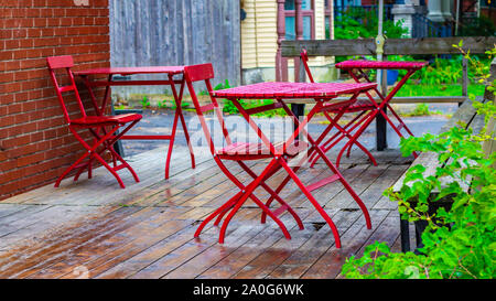 Les tables et les chaises rouges sont à l'extérieur d'un café (hors cadre) sur une terrasse. Banque D'Images