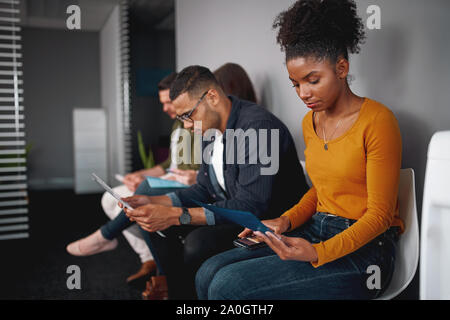 Les candidats de divers groupes se préparer à l'emploi interview assis sur des chaises dans la file d'attente Banque D'Images